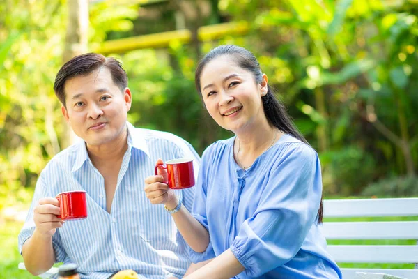 快乐的亚洲老夫老妻在绿色花园喝咖啡快乐的早晨 — 图库照片