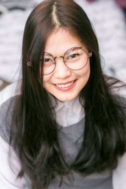 Asyalı güzel kadınların portresi rahat bir odada yatakta, gülümseyen kadınlar.