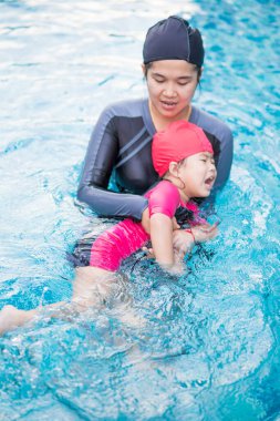 Havuzdaki küçük kız annesiyle ilk yüzme dersi için, etkinlik kızı.