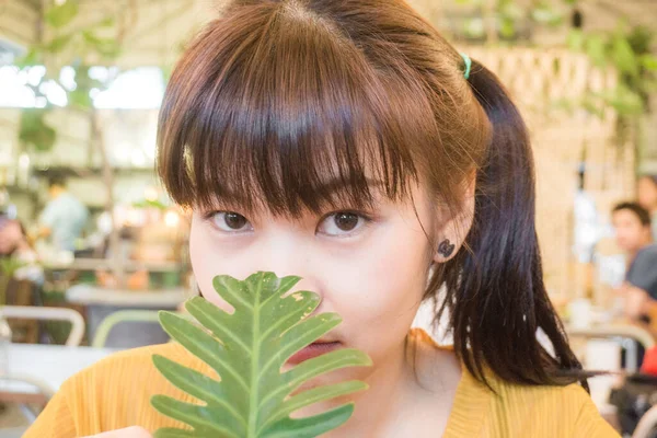 亚洲美丽的女人 带着绿叶在古老的咖啡馆里微笑 — 图库照片