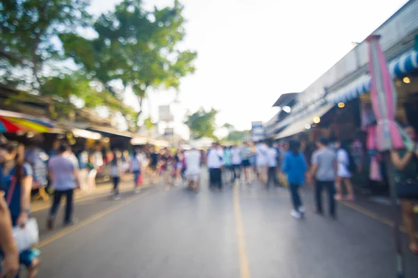 Blurred crowd of anonymous people walking on outdoor street market for shopping