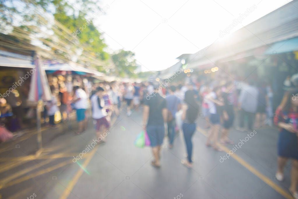 Blurred crowd of anonymous people walking on outdoor street market for shopping