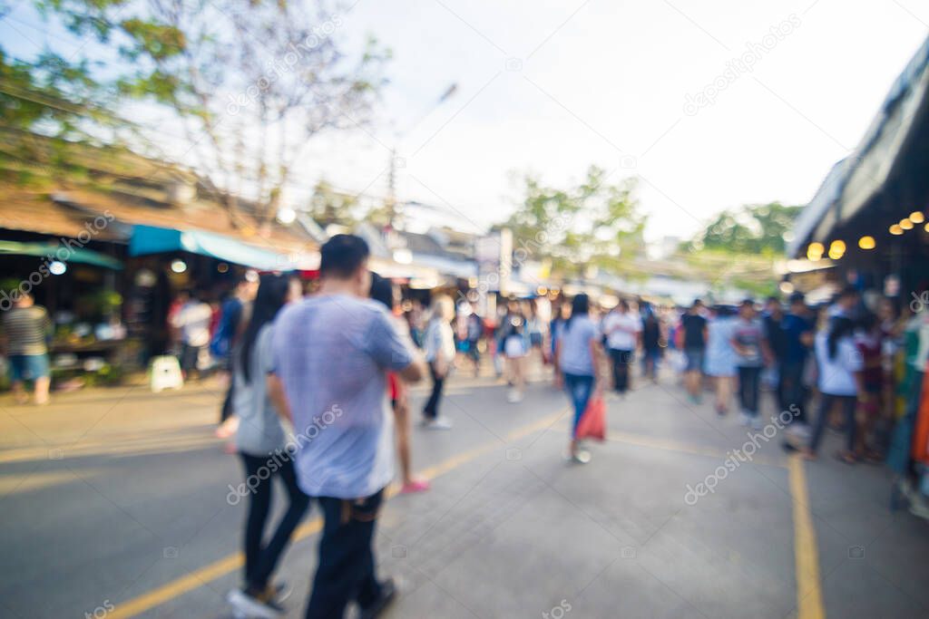 Blurred crowd of anonymous people walking on outdoor street market for shopping
