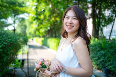 Güzel gülümseyen mutlu Asyalı kadın dinlenme günü parktaki güneş ışığı arka planı