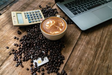 Ahşap masada çalışan laptoplu sıcak latte kahve.