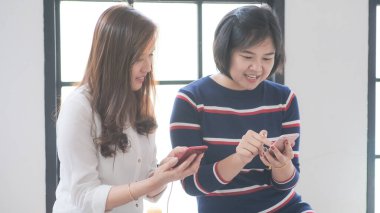 Casual business women use smartphone together talking online business, Happy business women