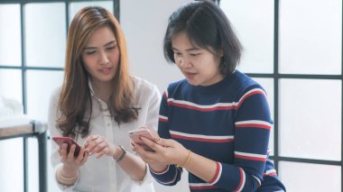 Casual business women use smartphone together talking online business, Happy business women