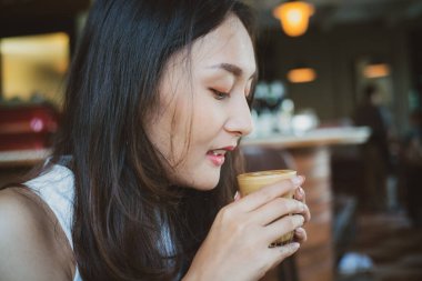 Asian women sitting in cafe drinkking hot latte coffee