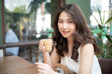 Asian women sitting in cafe drinkking hot latte coffee