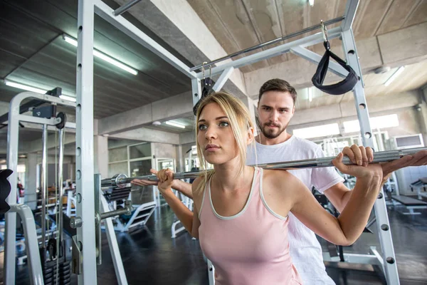 Sport women working out with pull barbell in  fitness gym Healthy women