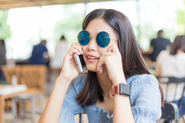 Kafede oturan Asyalı iş kadınları akıllı telefon kullanırlar.