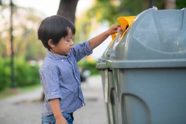 Çocuk çöp tenekesini şehir parkında temiz tutuyormuş.