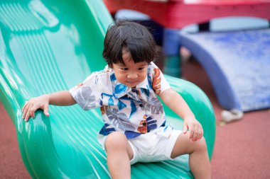Little asian boy playing in colorful playground outdoor public park child playing exercise
