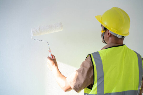Painter man painting on white wall interior working new house with copyspace