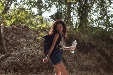 Kız ormanda yürürken doğanın tadını çıkarıyor ve su içiyor.