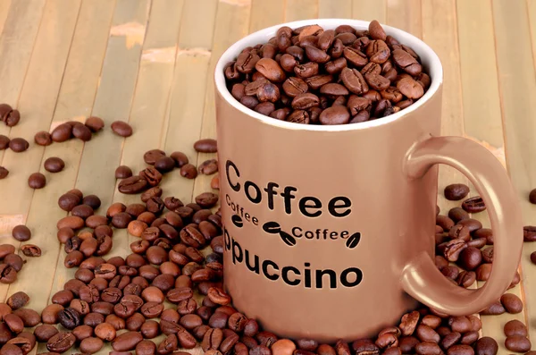 コーヒー豆と茶色のカップは木製のテーブル — ストック写真