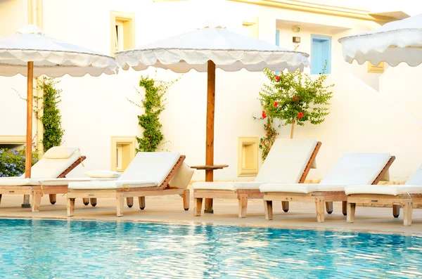 Lounge chairs by the pool at sunset time — Stock Photo, Image