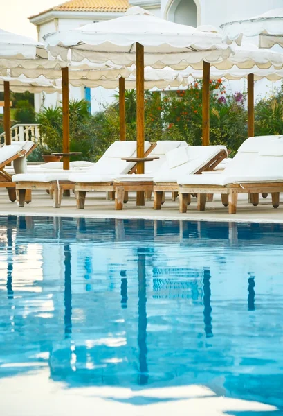 Lounge chairs by the pool at sundown time vertcal Stock Picture