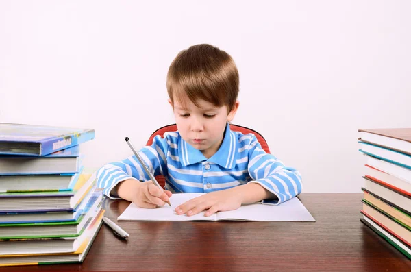 Jongen schrijft in werkboek — Stockfoto