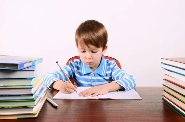 Jongen schrijft in werkboek — Stockfoto