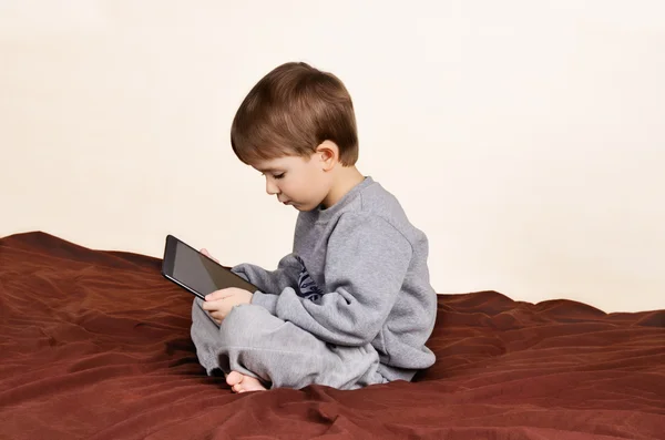 Menino sentado e brincando no tablet — Fotografia de Stock