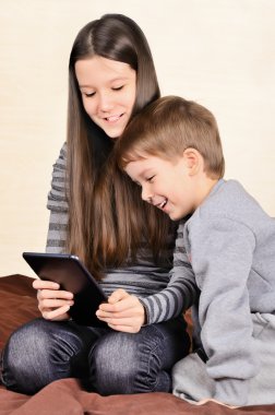 gülen çocuk ve tablet üzerinde oynayan kız