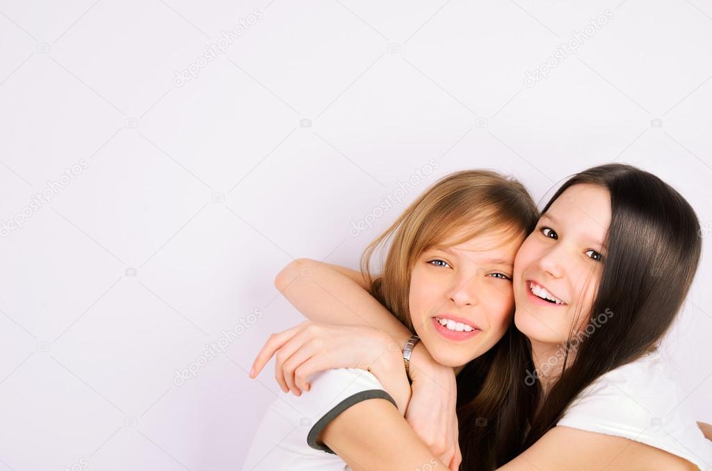 Blonde and brunette teen girls cuddling and laughing