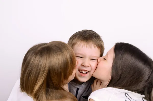 Två tjejer kysser lite skrattande pojke — Stockfoto