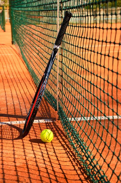 Pelota de tenis y raqueta están cerca de la red vertical — Foto de Stock