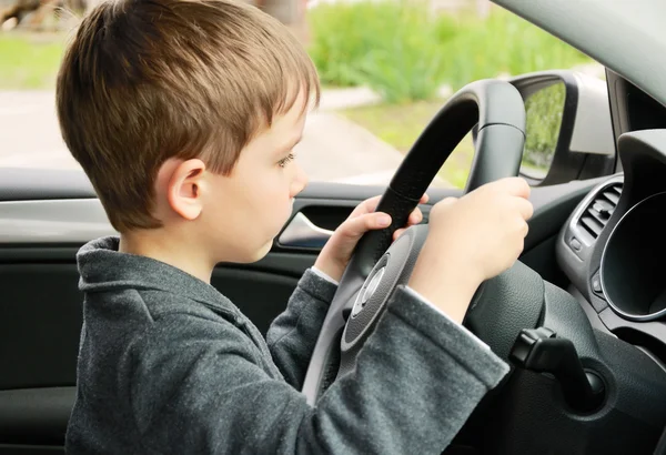 Мальчик за рулем автомобиля и смотрит на дорогу — стоковое фото