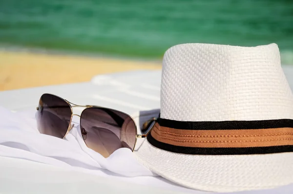White hat and sunglasses on the background of sea and sand — Stock Photo, Image