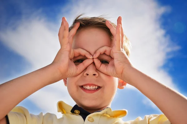 Lächelnder Junge hat Finger wie Ferngläser und schaut durch sie hindurch — Stockfoto