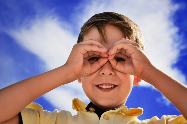 Chico sonriente hizo dedos como binoculares —  Fotos de Stock