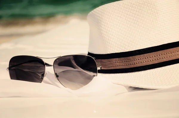 Toned image white hat and sunglasses on the background of sea an — Stock Photo, Image