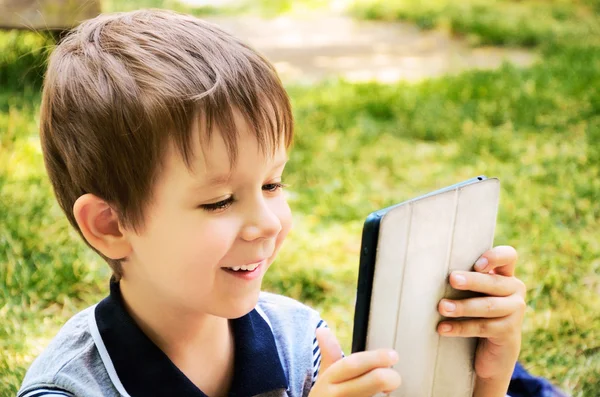 Menino olhando para tablet ao ar livre — Fotografia de Stock