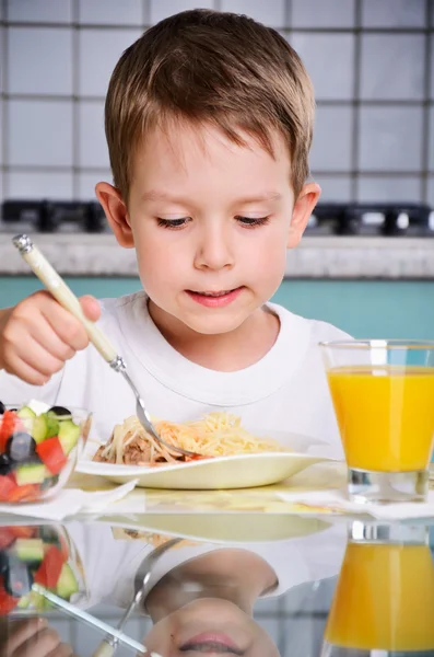 Pojken äta vid bordet, titta på plattan. vertikala — Stockfoto