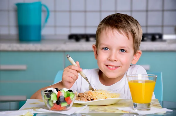 Sorrindo menino alegre sentado na mesa de jantar e olhando para o th — Fotografia de Stock