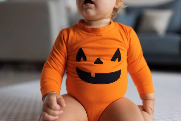 Χαριτωμένο καυκάσιο μωρό κοριτσάκι ενός έτους σε πορτοκαλί κοστούμι με πρόσωπο κολοκύθας στο σπίτι. Καλή ιδέα Απόκριες — Φωτογραφία Αρχείου