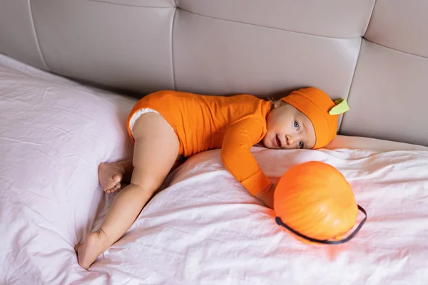 Schattig blank baby baby meisje van een jaar oud in oranje kostuum met pompoen gezicht thuis. Gelukkig Halloween concept — Stockfoto