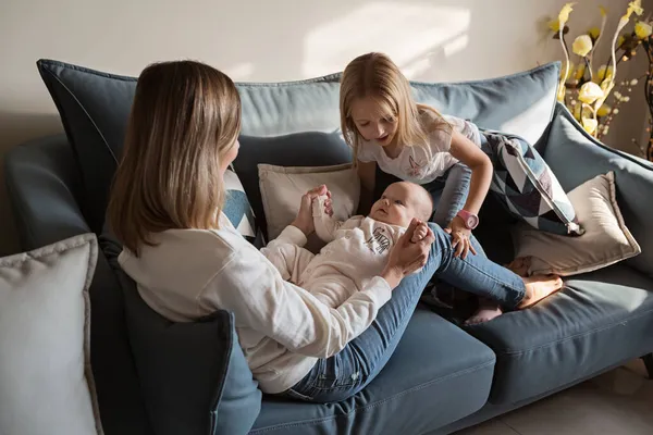 Jonge blanke moeder heeft plezier op de bank met twee kinderen thuis tijdens coronavirus covid-19 quarantaine. Sociale Afstandelijkheid en Zelfisolatie. Moederdag viering, weekend concept. — Stockfoto