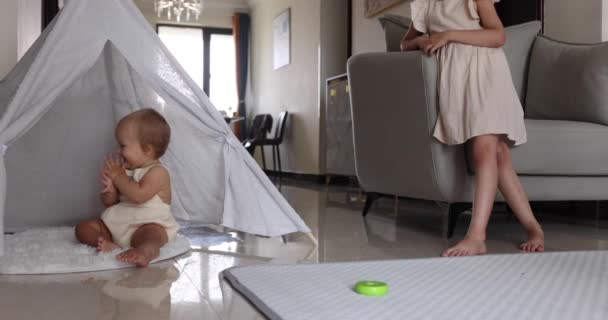 Dos lindos hermanitos caucásicos jugando juntos en wigwam en el suelo en casa. Concepto de desarrollo infantil. Bebé niña con el pelo rubio juega con la hermana mayor. cámara lenta 4k — Vídeos de Stock