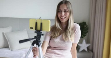 Sarışın, tripodu cep telefonuyla tutan ve sosyal medyada takipçilerle iletişim kuran ya da arkadaşlarıyla canlı sohbetler yapan, Coronavirus sırasında online ders alan mutlu, beyaz bir kadın.