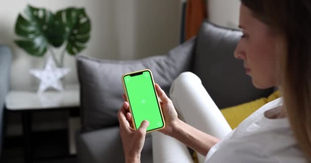 Młoda kobieta korzystająca z telefonu komórkowego z zielonym ekranem do zbliżenia przestrzeni kopiowania. Makieta klucza Chroma na smartfonie w dłoni. Osoba trzyma telefon komórkowy i kradnie zdjęcia lub zdjęcia w domu — Wideo stockowe