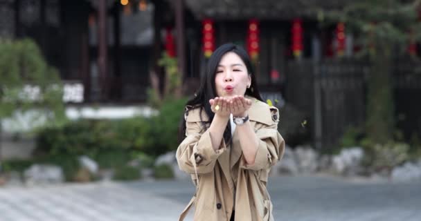 Életmód Portré fiatal ázsiai nő barna haj fúj arany konfetti szabadban. Szülinapot ünneplő személy, kínai újév 2022 vagy nemzeti ünnep október 1. Lassú mozgás. — Stock videók