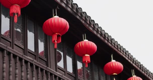 Edifício tradicional antigo decorado com lanternas vermelhas na China para o ano novo chinês ou celebração do festival da primavera. Luzes de papel orientais balançando com o vento no telhado do edifício. Movimento lento — Vídeo de Stock