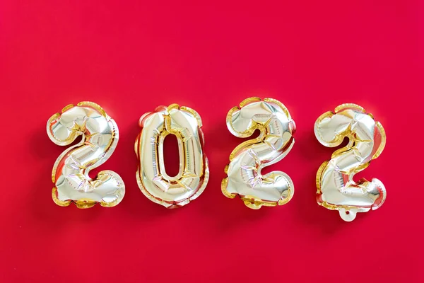 Happy new year 2022 background. Balon logam warna emas pada kertas merah. Datar berbaring, tampilan atas, mockup, overhead. Perayaan liburan musim dingin — Stok Foto