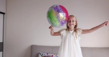 Hoş, sevimli, sevimli bir kızın, sekiz yaşındaki doğum gününü parlak ve renkli balonlarla kutladığı, günlük moda elbiseler giydiği bir fotoğraf. Çocuk eğleniyor. Yavaş çekim