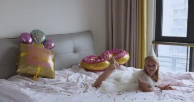 Hoş, sevimli, sevimli bir kızın, sekiz yaşındaki doğum gününü parlak ve renkli balonlarla kutladığı, günlük moda elbiseler giydiği bir fotoğraf. Çocuk eğleniyor. Yavaş çekim