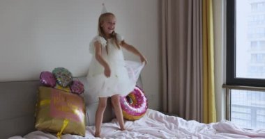 Hoş, sevimli, sevimli bir kızın, sekiz yaşındaki doğum gününü parlak ve renkli balonlarla kutladığı, günlük moda elbiseler giydiği bir fotoğraf. Çocuk eğleniyor. Yavaş çekim