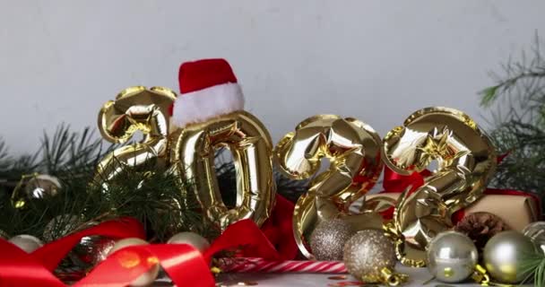 Gelukkig nieuwjaar 2022 achtergrond. Metalen ballonnen gouden kleur op grijs beton met confetti. Wintervakantie viering. — Stockvideo
